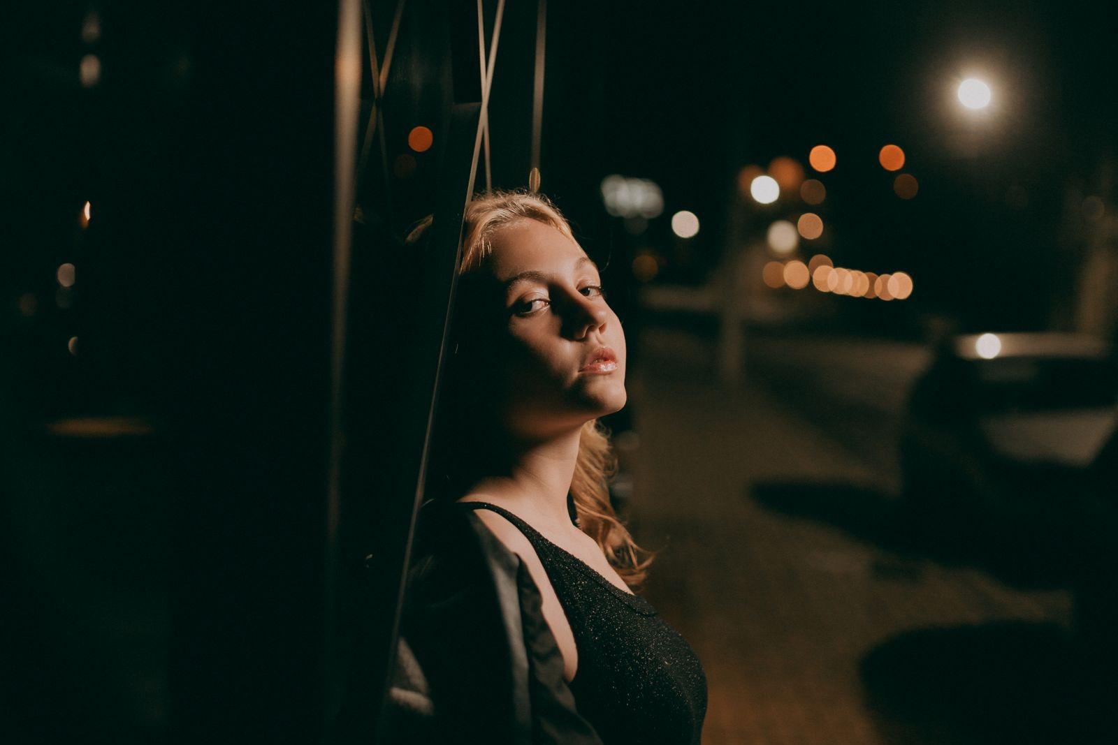 Class of 2027 senior posing for a cinematic after-dark portrait with warm city lights in Sacramento